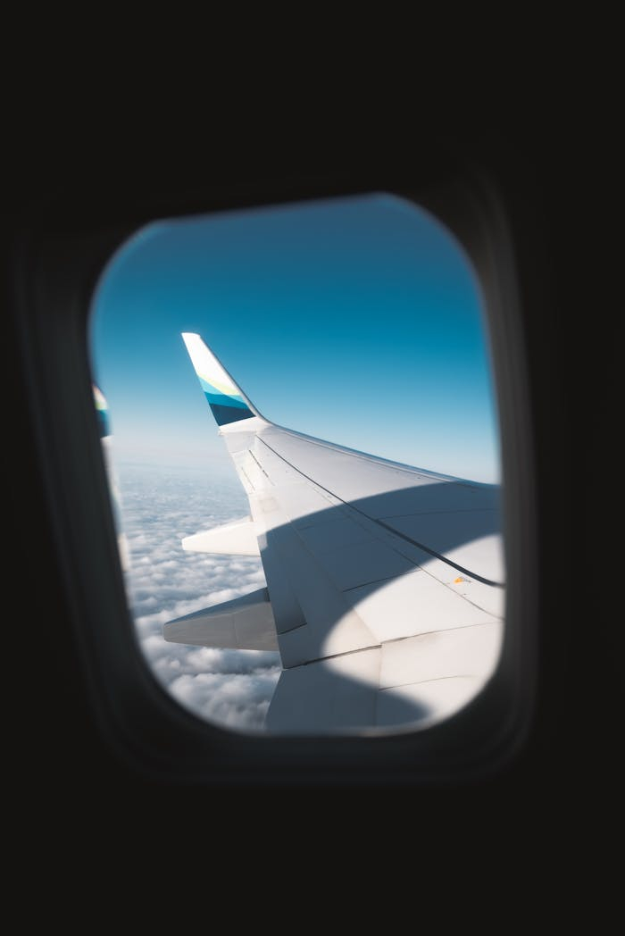 A stunning view from an airplane window capturing the wing and clouds below.