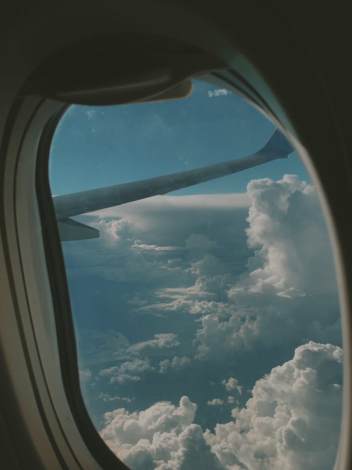 A scenic aerial view of clouds from an airplane window during a daytime flight.